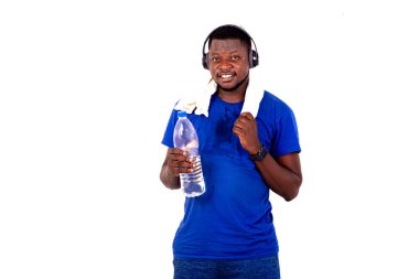 Boynunda havluyla ve kulaklıkla elinde plastik bir su şişesiyle gülümseyen yakışıklı bir genç adamın portresi..