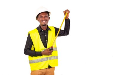 Genç marangoz yeşil yelek giyiyor ve elinde mezura tutarken gülümsüyor..