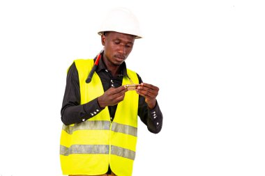 Genç marangoz yeşil yelek ve küçük bir kanca tutarken kaskı takıyor..