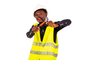 Yeşil yelek ve güvenlik kaskı takan genç bir teknisyen elinde çekiç ve tornavidayla gülümsüyor.