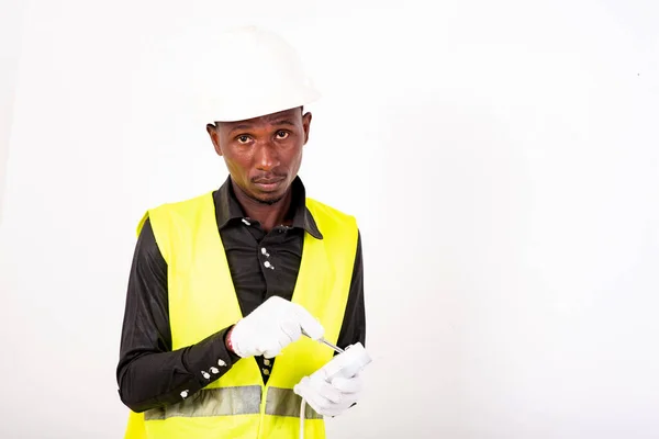 young male electrician wearing white glove while testing an extension cord with a voltage tester screwdriver.