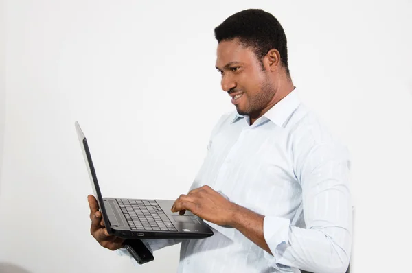 Молодой человек стоит и работает со своим ноутбуком . — стоковое фото