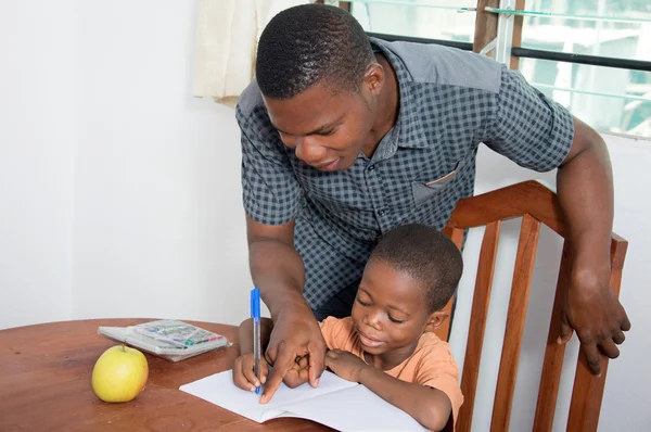 Tatínek pomáhá jeho dítě psát doma. — Stock fotografie