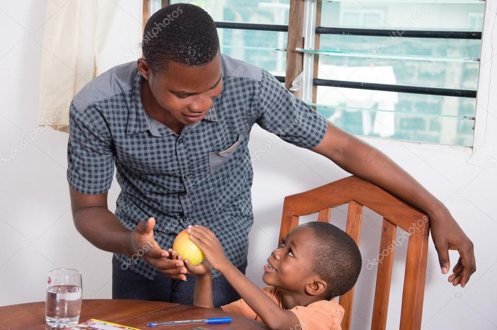 Child showing an apple to his father.