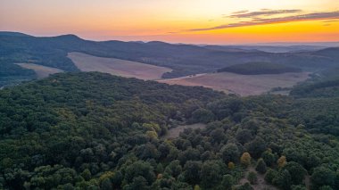 Macaristan 'daki Holloko kalesi etrafındaki ormanların günbatımı manzarası.