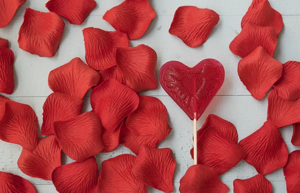 Lízátko srdce a nádherné okvětní lístek růže — Stock fotografie