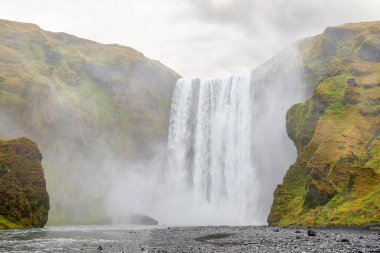 Bulutlu havada puslu Skogafoss şelalesi. Skogafoss İzlanda 'daki en büyük şelalelerden biridir.