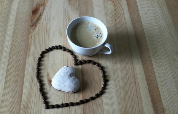 Cup of coffee and coffee grains in the form of heart