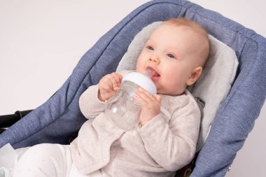 Güzel bebek, beyaz otlaklar için cam bir şişe tutuyor.