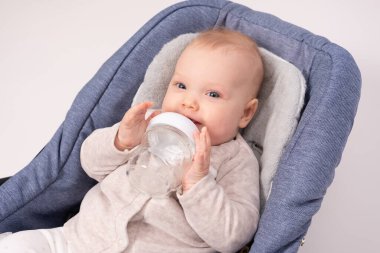 Güzel bebek, beyaz otlaklar için cam bir şişe tutuyor.