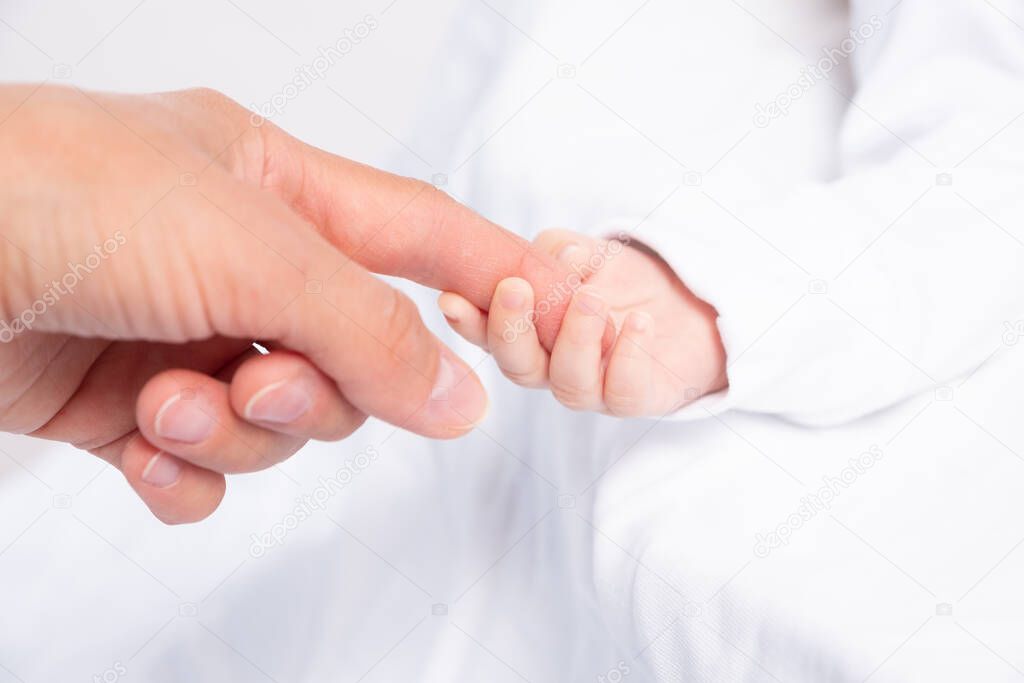 Baby holds a finger of mother, close-up shot