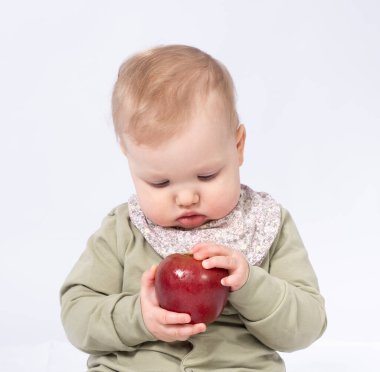 Güzel bebek bir elma tutuyor, beyaz bir arka plan.
