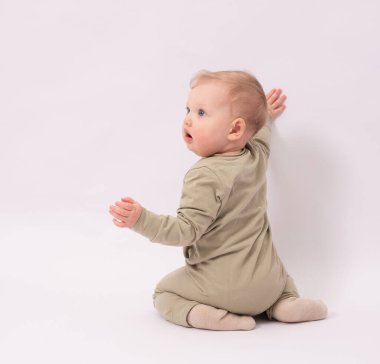 Sevimli bebek bir şey tarafından şaşırtılıyor ve beyaz zeminde oynuyor.