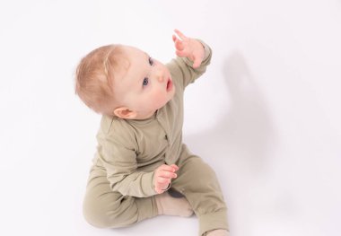 Sevimli bebek bir şey tarafından şaşırtılıyor ve beyaz zeminde oynuyor.