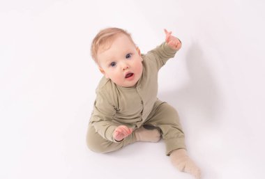 Sevimli bebek bir şey tarafından şaşırtılıyor ve beyaz zeminde oynuyor.