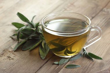 Bitki çayı ya da bitki özlü bitki çayı yakınındaki ahşap masada yaprak, yakın plan, fotokopi alanı, bitkisel içecekler ve naturopati konsepti.