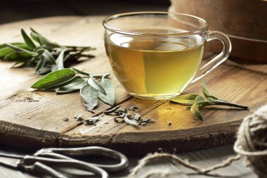 Bitki çayı ya da bitki özlü bitki çayı yakınındaki ahşap masada yaprak, yakın plan, fotokopi alanı, bitkisel içecekler ve naturopati konsepti.