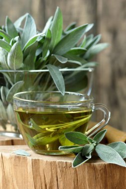 Sage bitkisel yaprak çayı ya da yakınındaki kırsal ahşap, fotokopi alanı, bitkisel içecekler ve naturopati konsepti üzerinde bitki yapraklarıyla gargara yapmak.