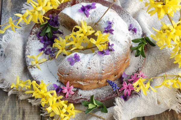 Spring holiday cake decorated with spring may flowers: forsythia, hyacinth and violet, closeup, copy space, egg free vegan baking and easter festive food dessert concept