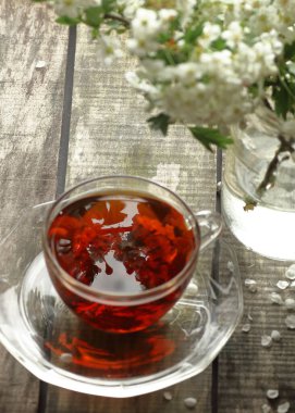 Bahar çiçekli Hawthorn bahar çiçekli çay, çiçek tomurcukları ile ahşap arkaplanda, çaydaki çiçek yansımasına odaklan, yakın plan, kopya alanı, dikey, bitkisel çaylar ve doğal tıp konseptine odaklan