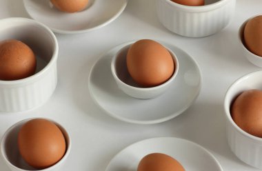 Yumurta ve seramik beyaz tabaklar ve beyaz arka planda tabaklar, geometrik izometrik modern sanat tasarımı ile Paskalya soyut minimalist konsept deseni