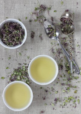 Kekik kurutulmuş çiçek çayı keten tekstil bardaklarında, yakınlarda çiçekler ve kaşık, yakın plan, kopyalama alanı, düzlük, yukarıdan bakıldığında, sağlıklı bitkisel çaylar ve doğal destek konsepti.