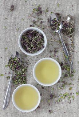 Kekik kurutulmuş çiçek çayı keten tekstil bardaklarında, yakınlarda çiçekler ve kaşık, yakın plan, kopyalama alanı, düzlük, yukarıdan bakıldığında, sağlıklı bitkisel çaylar ve doğal destek konsepti.