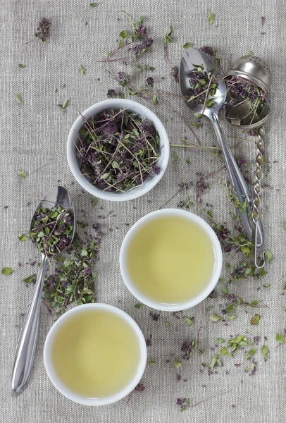 Kekik kurutulmuş çiçek çayı keten tekstil bardaklarında, yakınlarda çiçekler ve kaşık, yakın plan, kopyalama alanı, düzlük, yukarıdan bakıldığında, sağlıklı bitkisel çaylar ve doğal destek konsepti.