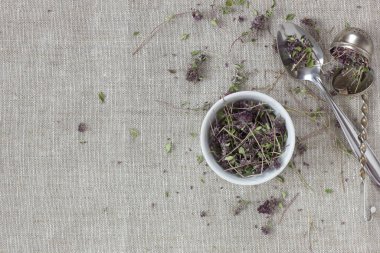 Kekik kurutulmuş çiçek çayı keten tekstil üzerine beyaz bir kasede yakın çiçekli ve kaşıklı, yakın çekim, kopyalama alanı, düzlük, yukarıdan bakıldığında sağlıklı bitkisel çaylar ve doğal destek konsepti.
