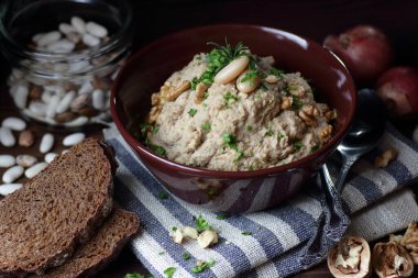 Böbrek fasulyesi ezmesi ya da aperatif olarak ceviz ve kızarmış soğan ile koyu siyah karamsar arka planda keten tekstil, yakın plan, fotokopi alanı, vejetaryen ve ödünç gıda konsepti