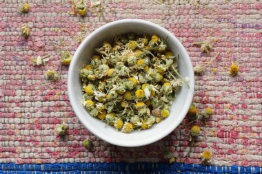 Yukardan, yukarıdan, yukarıdan, yukarıdan, düz, kapalı, doğal, homeopati ve doğal tıp konsepti üzerinde dokuma pamuklu pembe kumaş bir kasede papatya çiçekleri.