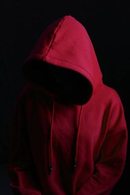 Kırmızı kapüşonlu, kapüşonlu, karamsar arka planda yüzü olmayan kadın şiddeti, insan hakları, feminizm kavramı.