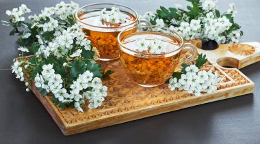 Çiçek tomurcuklarından gelen bitkisel dikenli çay. Kırsal arka planda, tahta kesme tahtasında çiçek açan dallar, fotokopi alanı, kalp sağlığı ve sağlıklı bitkisel içecekler konsepti.