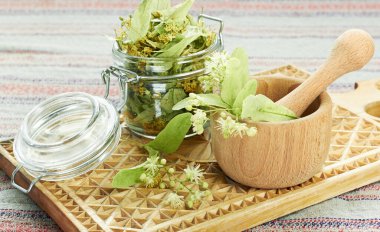 Bitkisel şifalı çay ve cam konserve için Linden çiçeği yanında kurutulmuş bitki konservesi kırsal ahşap kesim tahtası, arka ışıklandırma, yakın çekim, kopyalama alanı, alternatif tıp ve naturopati kavramı.