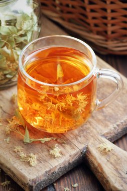 Ağaç kabında çiçekli ıhlamur çayı yakınlarda limon çiçeği, kuru ot, rahatlamak için yakın plan, zihinsel sağlık, naturopati, homeopati ve halk sağlığı konsepti.