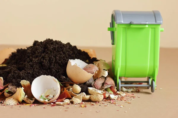 Organic waste, heap of biodegradable food compost with decomposed organic matter on top and green bin near, closeup, zero waste, eco friendly, waste recycling concept