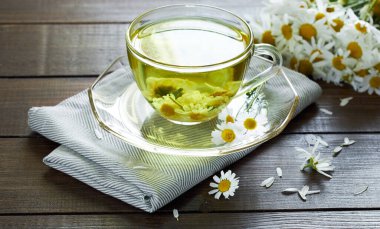 Papatya çayı, çiçek tomurcukları yakınlarda ahşap masa üzerinde tekstil ve papatya buketi, yakın plan, kopyalama alanı, sağlıklı bitkisel içecekler ve doğal şifacı konsepti.