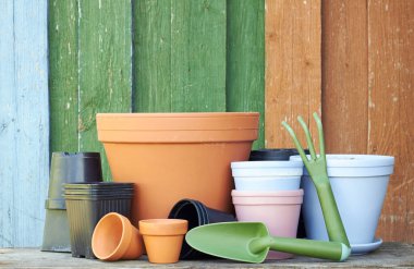 Terracotta kil saksıları ile siyah plastik kaplar ve bahçe aletleri ahşap masa üzerinde renkli parlak rustik arka plan, çocuk odası ve bahçe konsepti, yakın plan, kopyalama alanı
