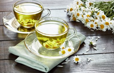 Tekstil ve papatya buketi, fotokopi alanı, sağlıklı bitkiler ve doğal şifacı konsepti olan ahşap masanın üzerinde çiçek tomurcukları bulunan papatya çayı veya bitki çayı.