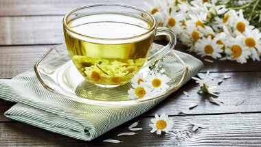 Tekstil ve papatya buketi, fotokopi alanı, sağlıklı bitkiler ve doğal şifacı konsepti olan ahşap masanın üzerinde çiçek tomurcukları bulunan papatya çayı veya bitki çayı.