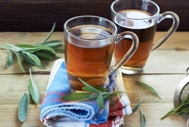 Kırmızı peçete ve ahşap masa, fotokopi alanı, alternatif tıp ve naturopati konsepti ile çevrili keten mavi yapraklı iki bardak bitkisel çay ya da decoction