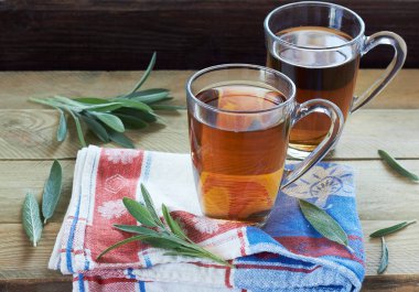 Kırmızı peçete ve ahşap masa, fotokopi alanı, alternatif tıp ve naturopati konsepti ile çevrili keten mavi yapraklı iki bardak bitkisel çay ya da decoction