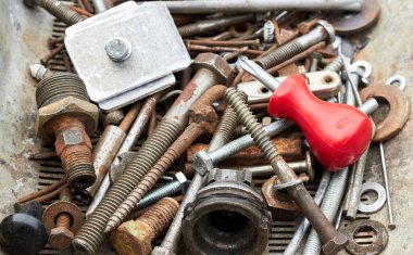 Metalik paslanmış endüstriyel atık: paslı cıvatalar ve kırmızı vida ile fındıklar üst rafta, yakın plan, kopyalama alanı, geri dönüşüm donanımı arka planı