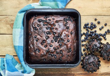 Çikolatalı yaban mersinli kek ve çörekler yabani orman meyveleri ile birlikte ahşap masa üzerinde, düz, yukarıdan bakıldığında, yakın plan, kopyalama alanı, ev yapımı vejetaryen yumurtasız pasta konsepti