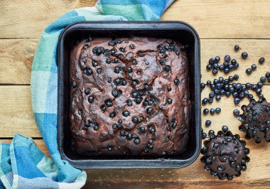 Çikolatalı yaban mersinli kek ve kırsal ahşap masa üzerinde yabani orman meyveleri, düz döşeme, yukarıdan bakıldığında, yakın çekim, kopyalama alanı, ev yapımı vejetaryen yumurtasız pasta konsepti