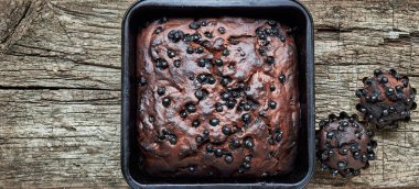 Kırsal ahşap arkaplanda kapkekleri olan çikolatalı yaban mersinli pasta, yukarıdan bakıldığında düz yatak, yakın çekim, fotokopi alanı, ev yapımı vejetaryen yumurtasız pasta konsepti