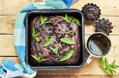 Naneyle süslenmiş çikolatalı yaban mersinli kek, az önce sade ahşap masa üzerinde pişmiş, düz, yukarıdan bakıldığında, yakın plan, fotokopi alanı, ev yapımı sağlıklı tatlı konsepti