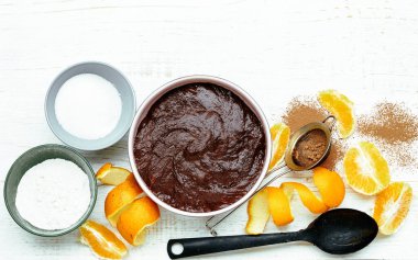 Beyaz ahşap masa üzerinde portakal suyu, kabuk ve mutfak gereçleri ile çikolatalı yumurtasız kekin malzemelerini pişirmek, düz uzanmak, üstten bakmak, yakın çekim, kopyalama alanı. Vejetaryen yemeği ve sağlıklı hamur işi kavramı