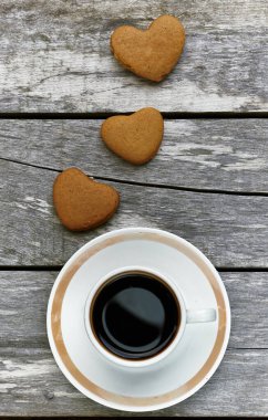 Kalp şeklinde zencefilli kurabiyeler mevcut bir kutuda; kahve ve kitaplar yakındaki ahşap masada, düz yerde, yukarıdan üst görünümde, tatil konseptinizin keyfini çıkarın