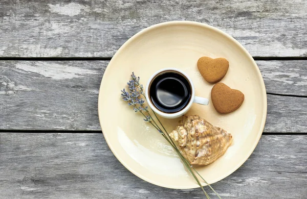 Scandinavian breakfast at the sea: coffee, heart shaped cookies, lavender and a shell on old weathered wooden table, enjoy simple moments of your life concept